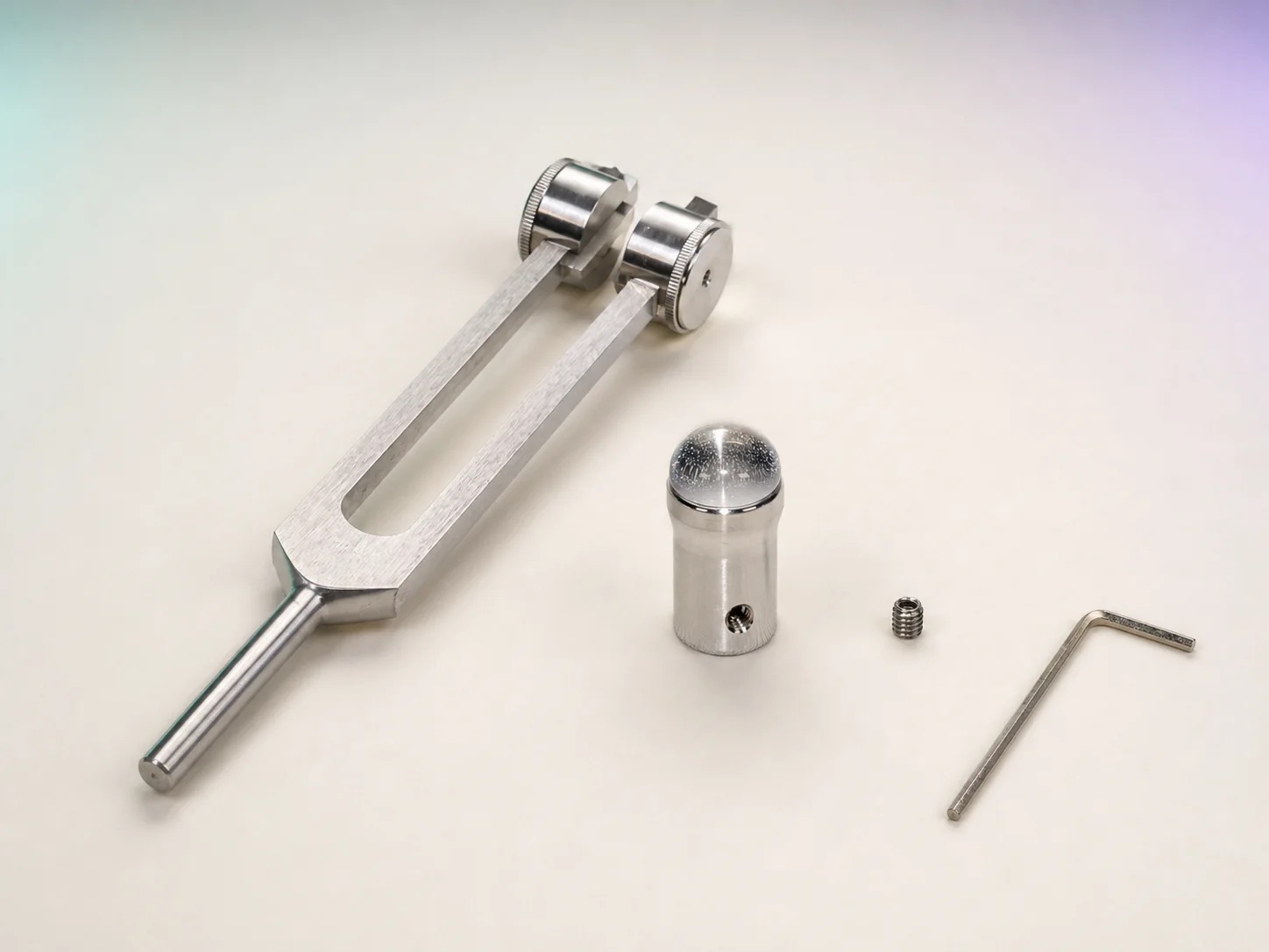 A weighted BioSonics-style Otto tuning fork, clear-quartz Gem Foot, set screw, and Allen wrench arranged separately.