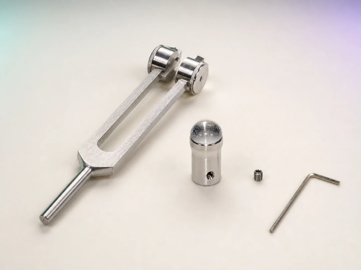 A weighted BioSonics-style Otto tuning fork, clear-quartz Gem Foot, set screw, and Allen wrench arranged separately.